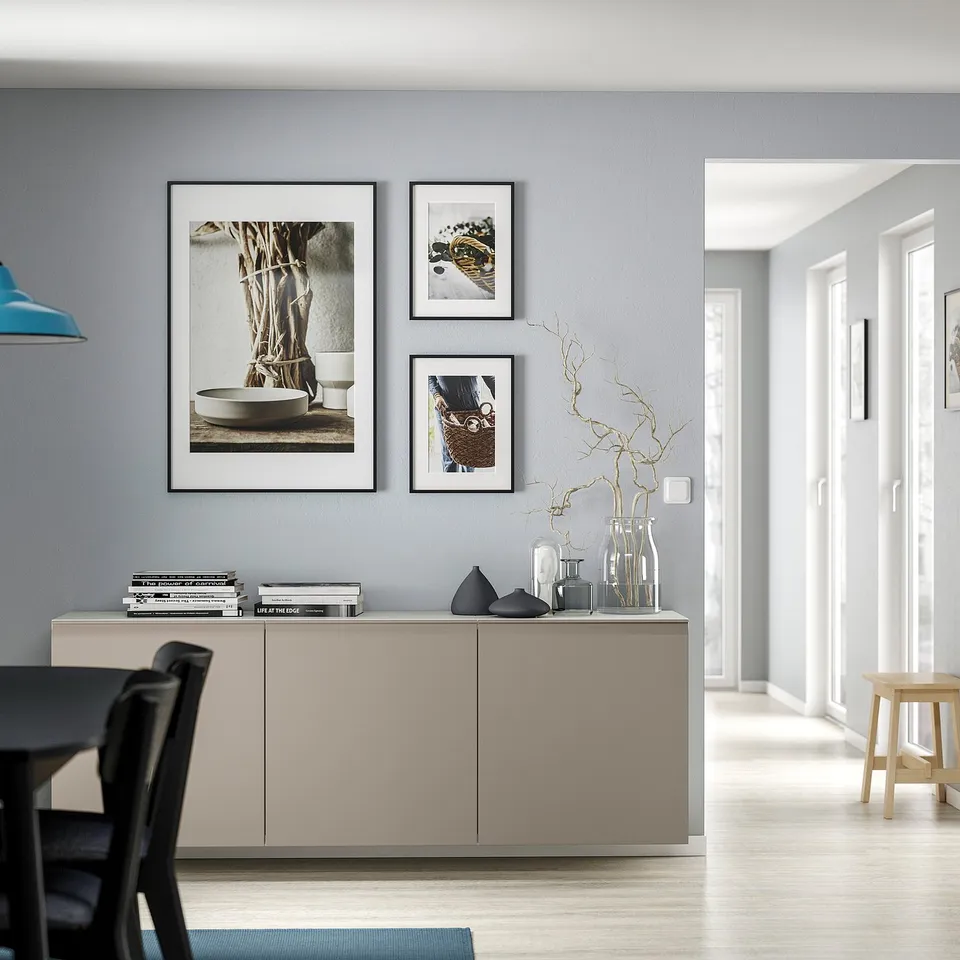Modern living room with BESTÅ unit, vases, books, art, lamp, stool, chairs.