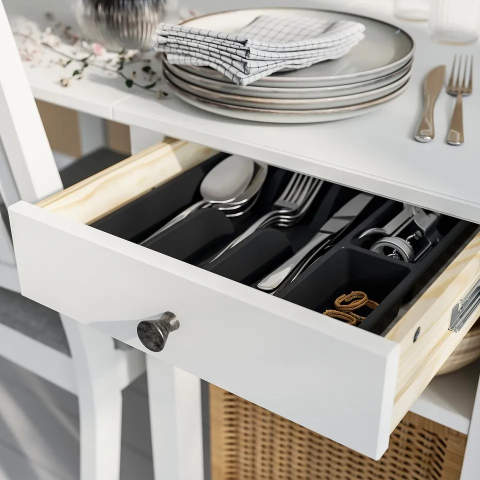 Open white drawer with organised cutlery compartments.