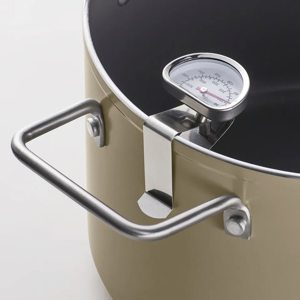 Close-up of a high-quality, gold-colored skillet with a temperature gauge and sturdy handles, perfect for frying.