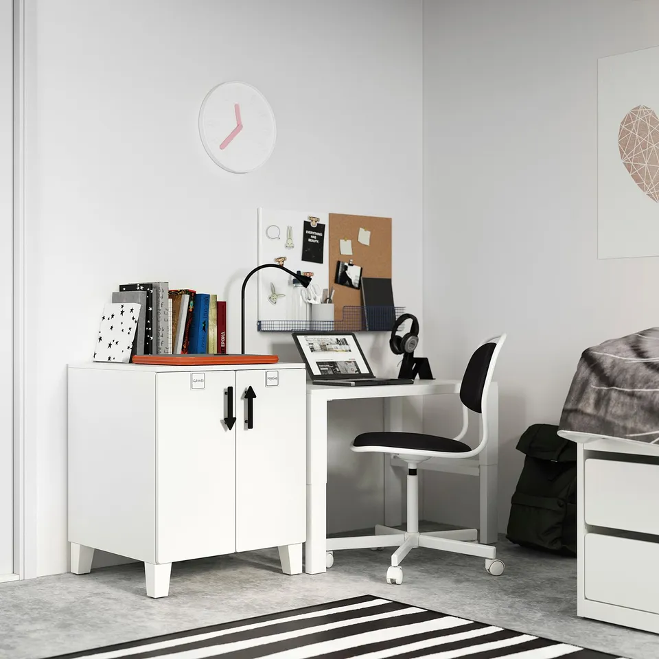 Minimalist white desk setup with adjustable chair, laptop, books, and clock on wall.