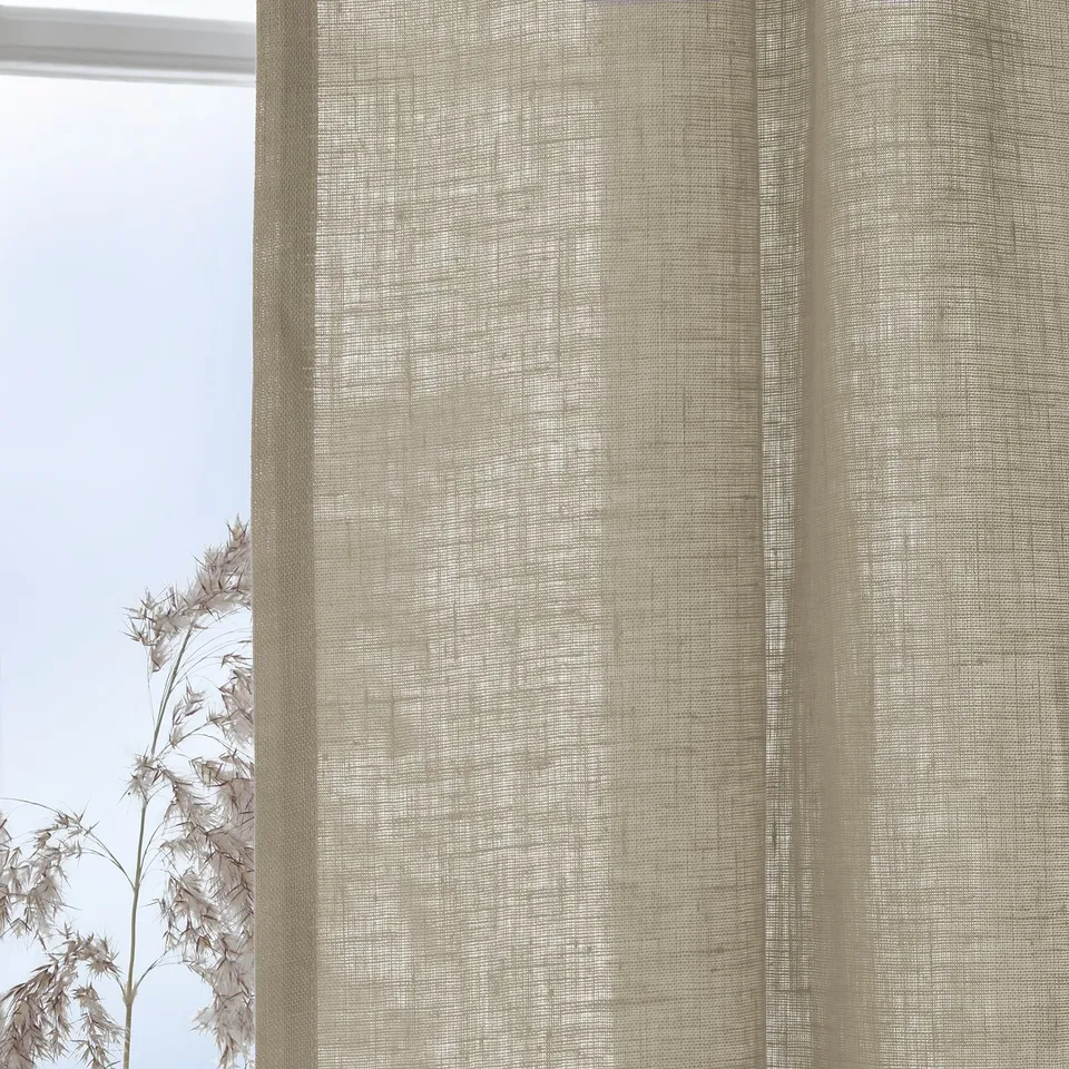 Sheer beige curtains hang by a window, filtering daylight and offering privacy.