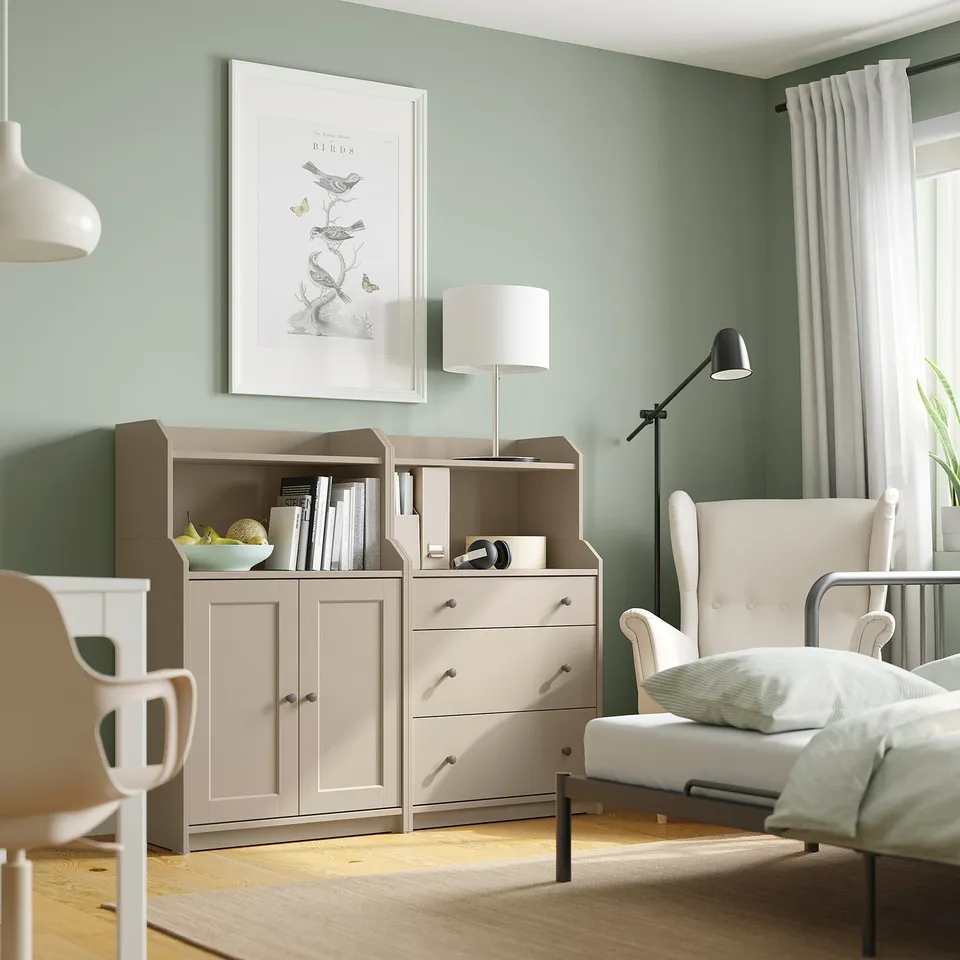 A cosy room with a white HAUGA chest of drawers, beige storage unit, and a white armchair.