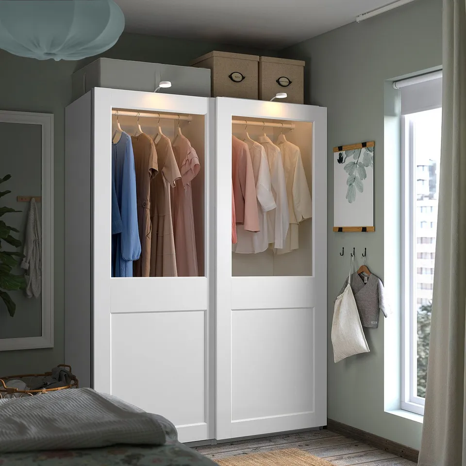 Bedroom with large white PAX wardrobe, neat clothes, built-in lights.
