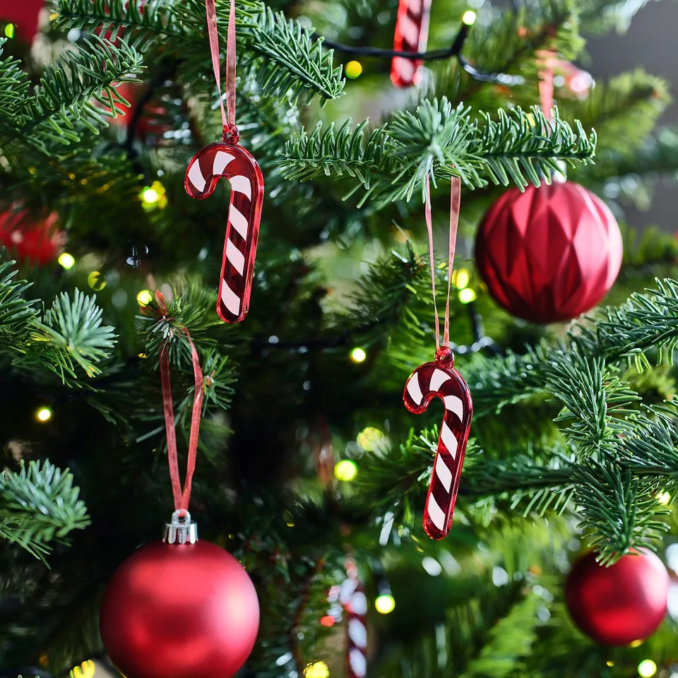 Christmas tree with red baubles, candy canes, lights, and pine branches.
