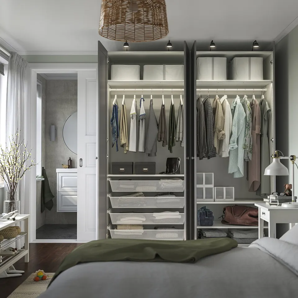 Modern bedroom with open wardrobe showcasing clothes, drawers, and organised storage. Integrated lighting highlights neatly arranged items.