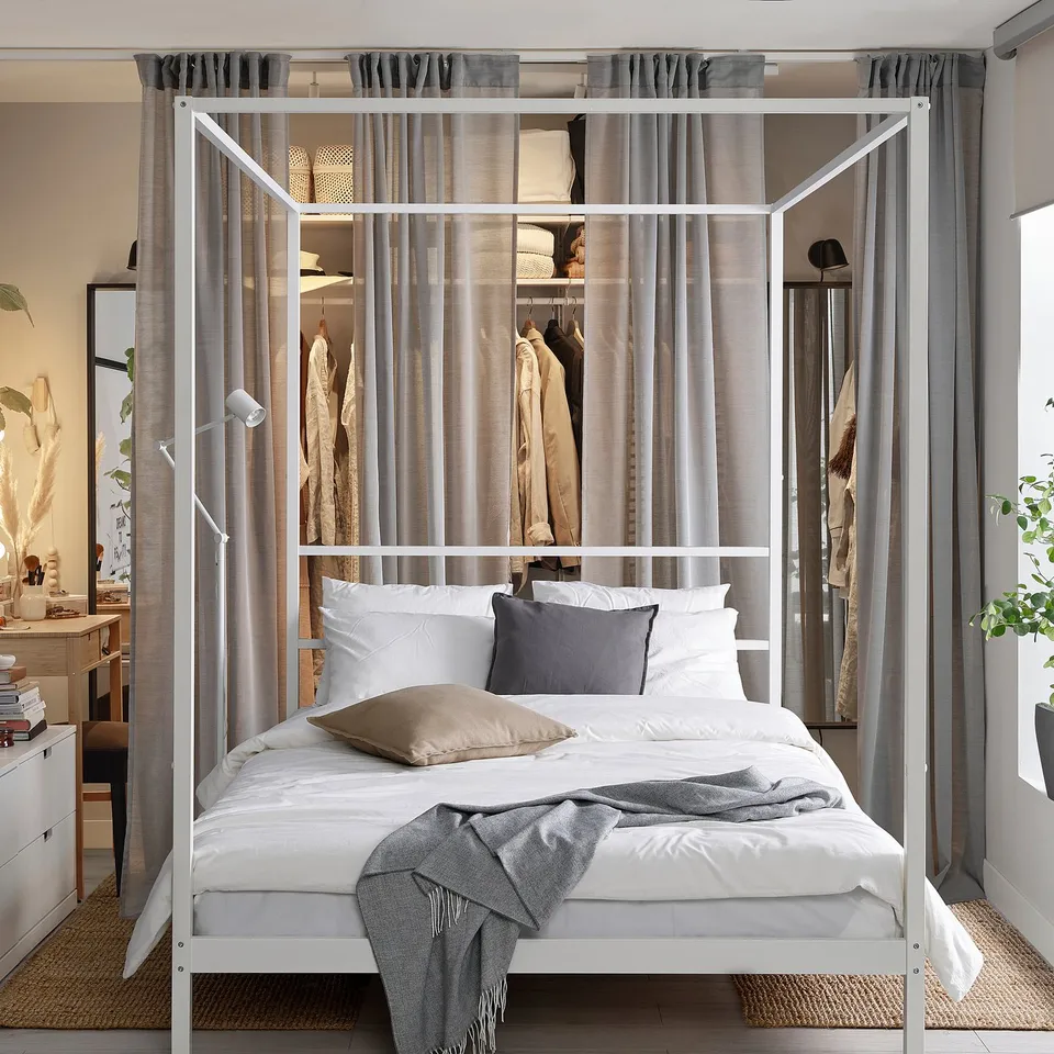 VITARNA bed with white frame, sheer grey curtains, and wardrobe. Minimalist design, slatted base, white linens, grey throw.