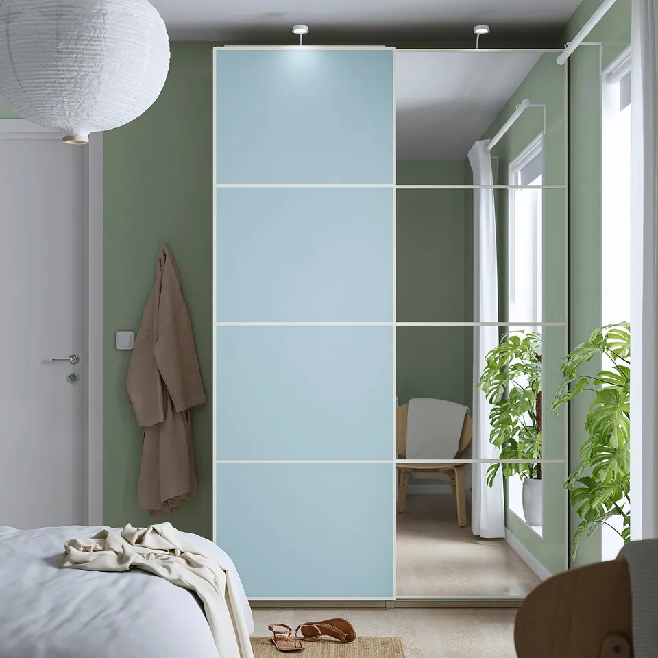 Modern bedroom with blue glass-panel door from MEHAMN/AULI collection, surrounded by green walls and plants.