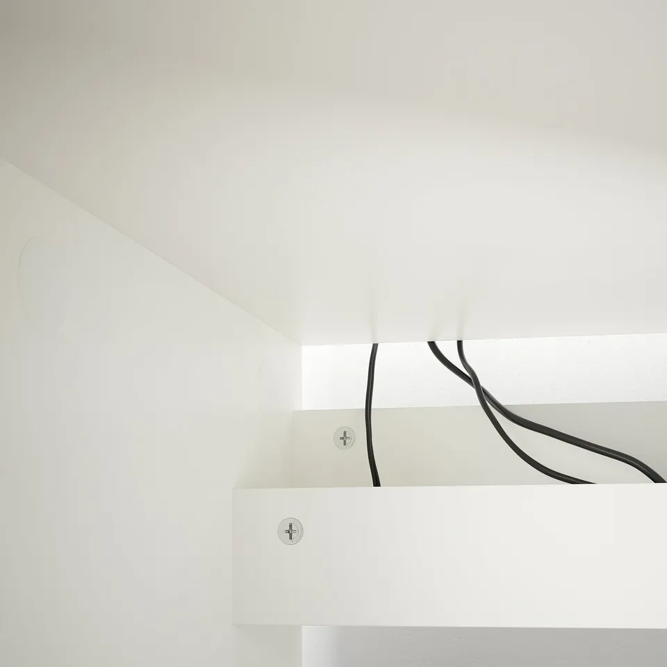 White desk with cables neatly organised under the tabletop, promoting a tidy workspace.