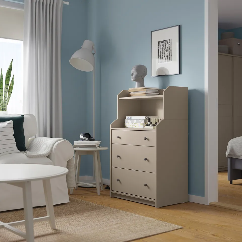 A modern living space a grey HAUGA chest with 3 drawers and top shelf against blue walls.