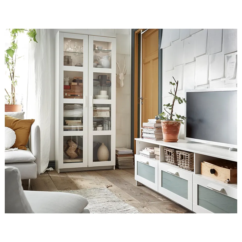 Modern living room with white BRIMNES storage, tv, and plants by large window.