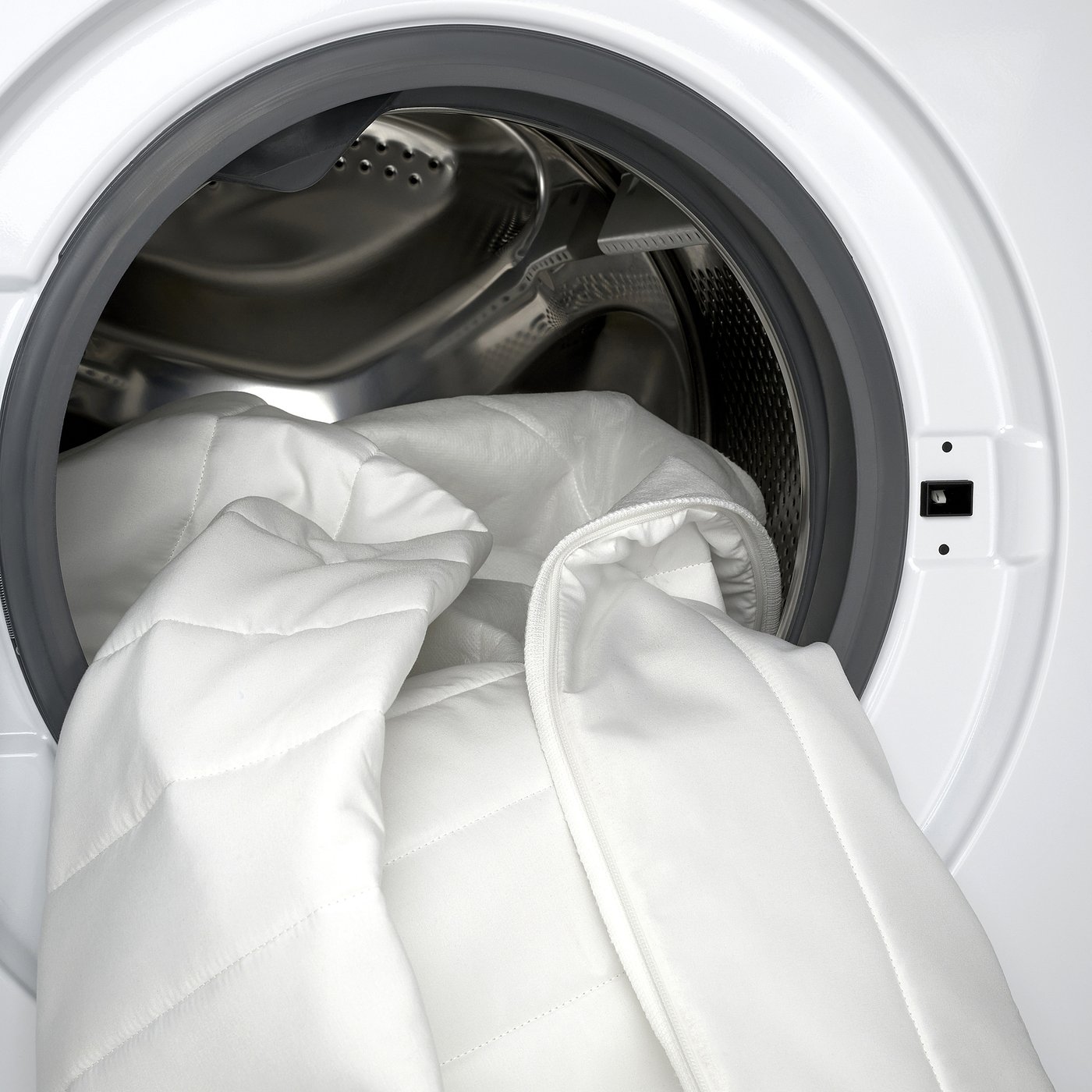White NÄSFJÄLLET mattress topper in washing machine, provides comfort, removable & washable cover.