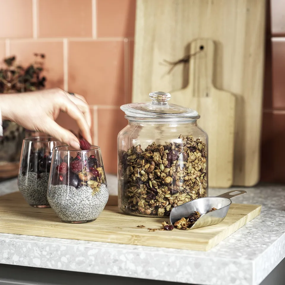 Pouring granola from jar onto chia pudding.