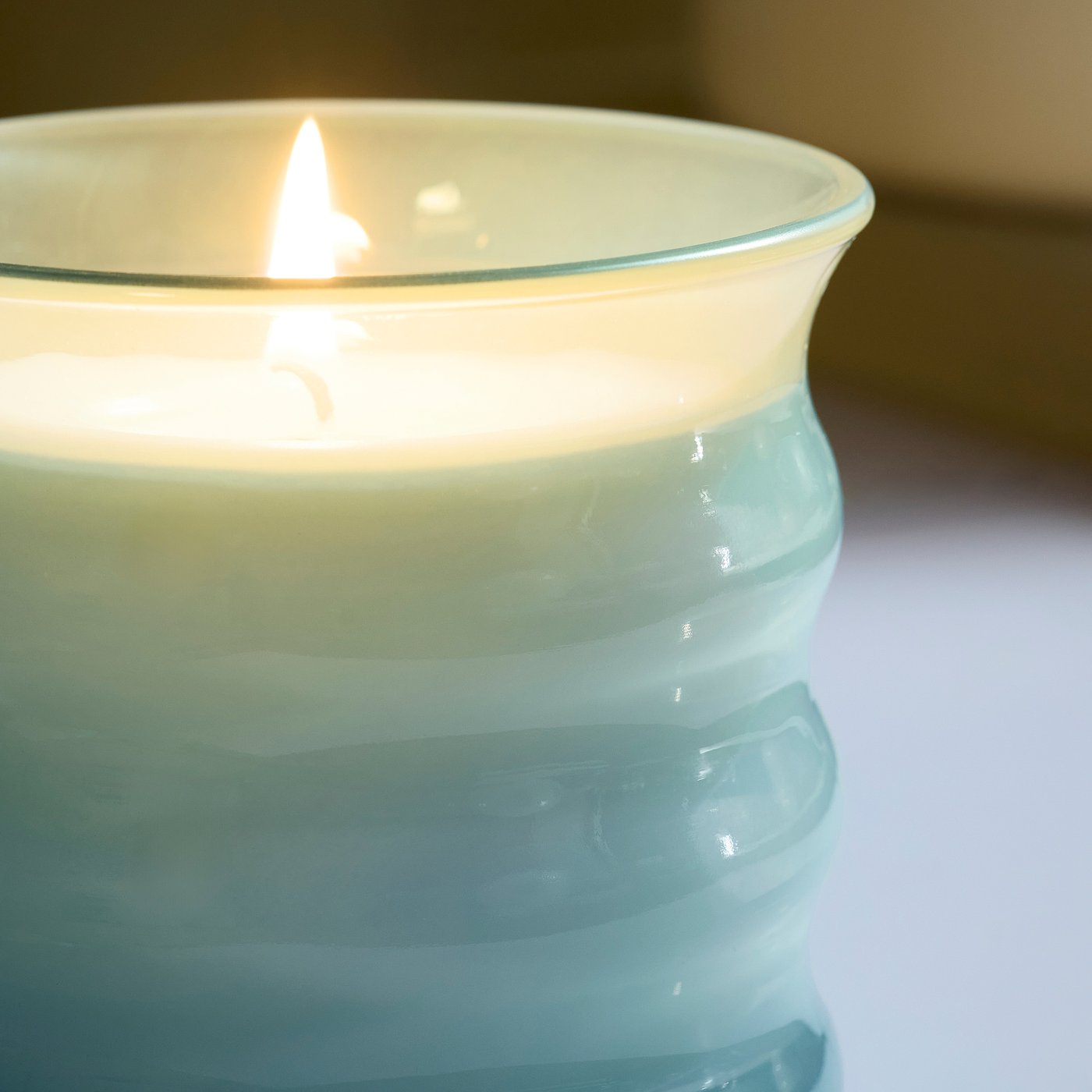 Elegant lit candle in frosted glass, with a clean, inviting glow. Ideal for cosy nights.