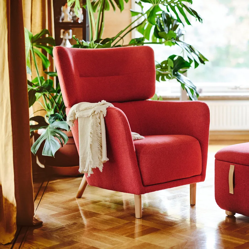 Bright red OSKARSHAMN armchair, large and comfortable, with wooden legs and a cosy throw blanket. Tall, plush, and inviting.