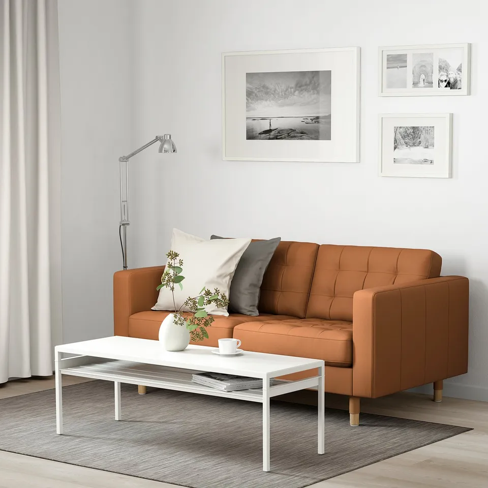 Modern living room with brown leather sofa, white coffee table, and wall art.