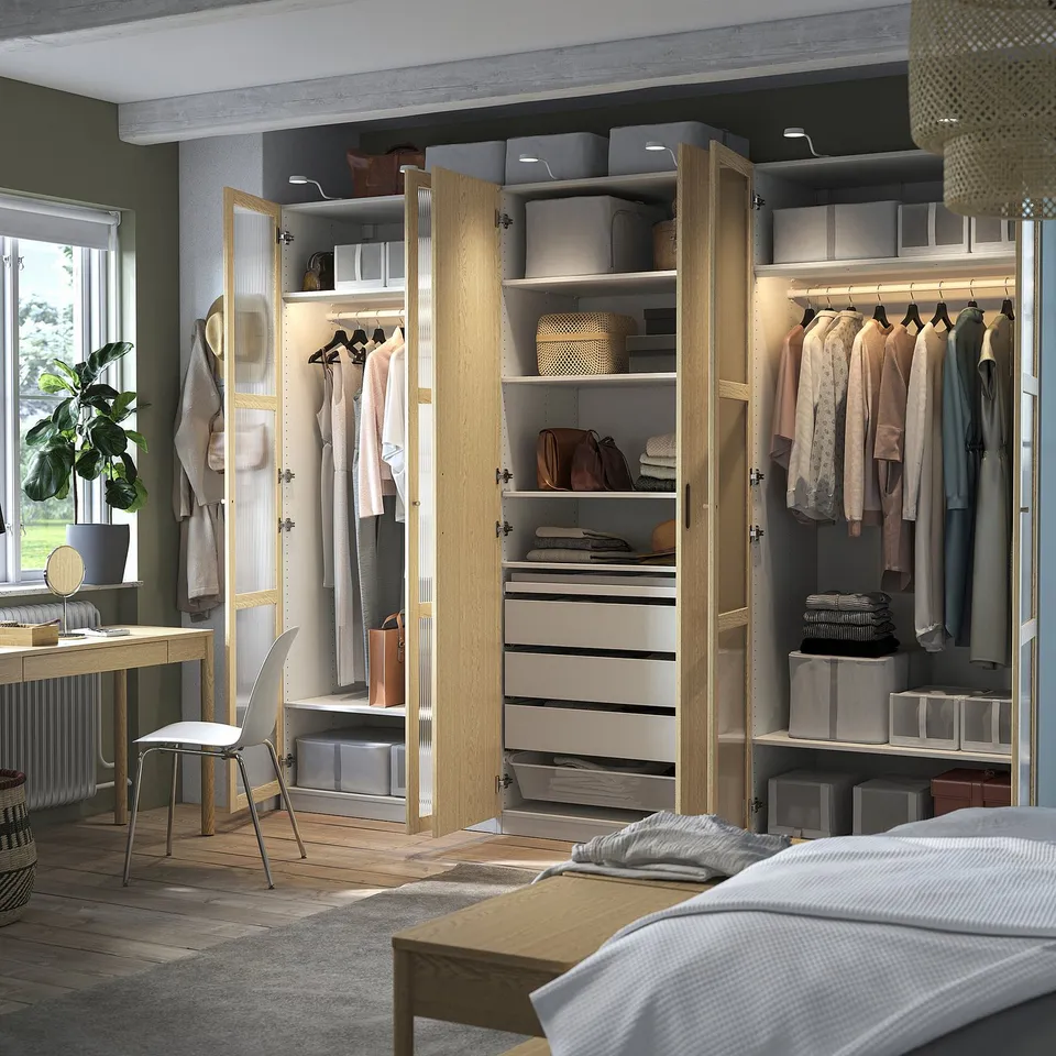 Modern bedroom with open wardrobe showing clothes, shelves, and organised storage solutions.