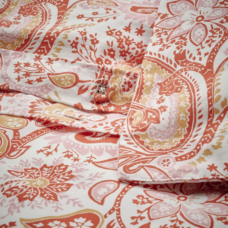 Folded paisley-patterned duvet cover with fabric buttons, showing envelope closure design.