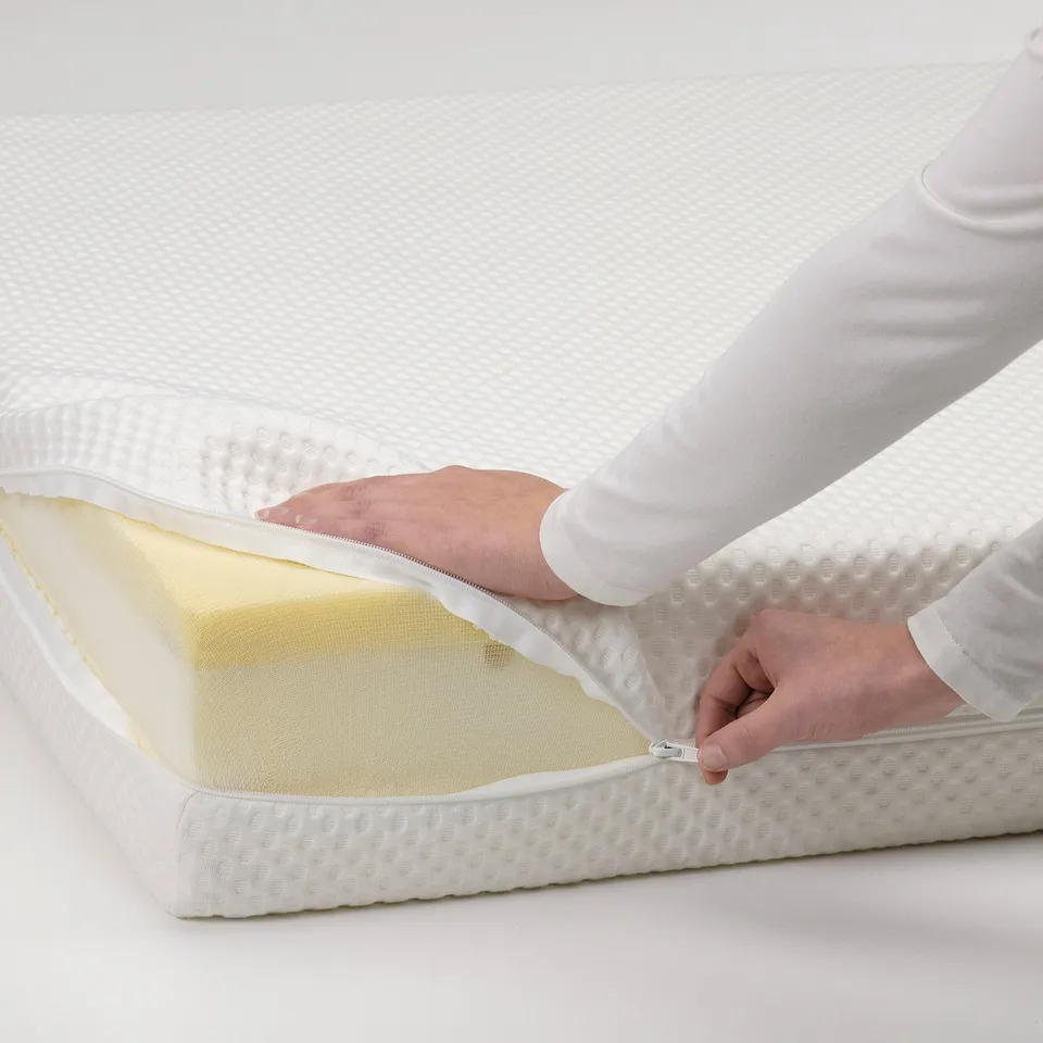 Person zips open white mattress, revealing foam layers.