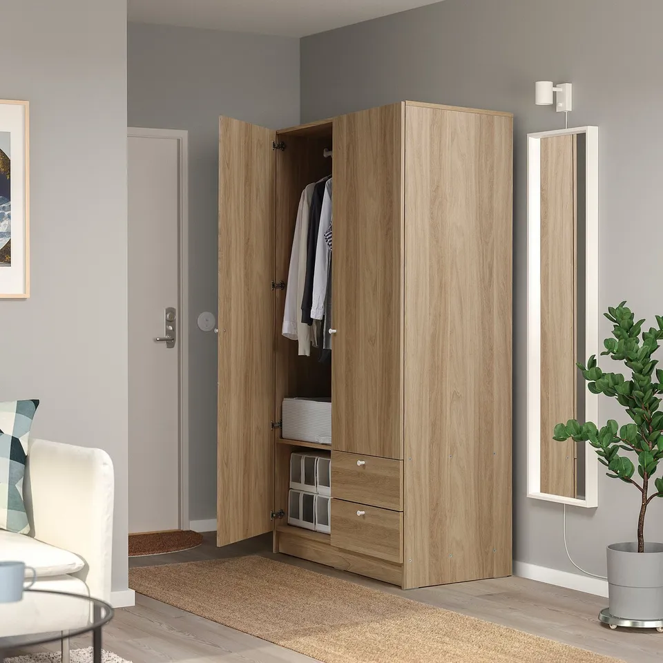 VILHATTEN wardrobe, light brown, open with clothes, fits in corner with chair and mirror.