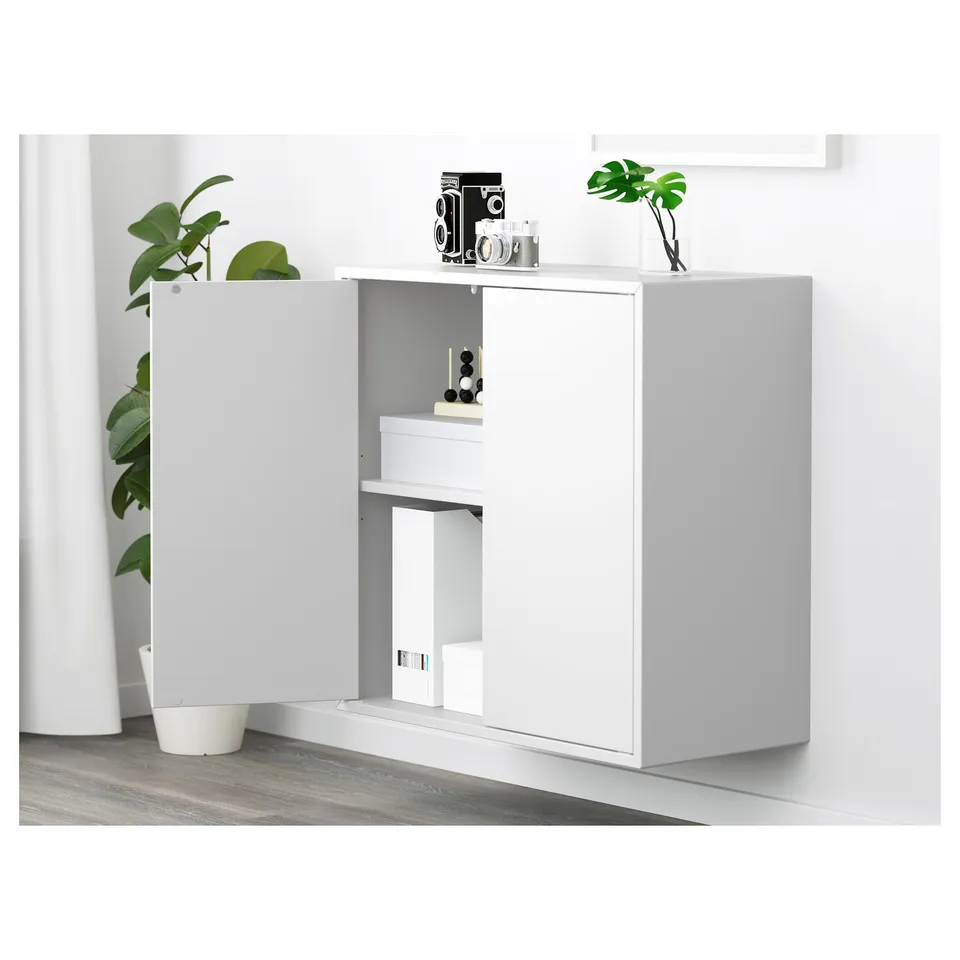 White EKET cabinet with two open compartments, one shelf visible, displayed with plants and vintage cameras.