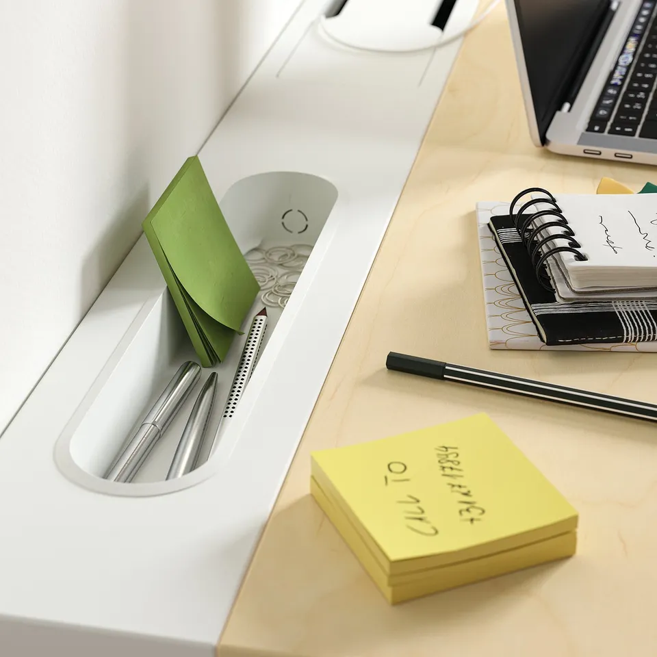 Desk with pens, notepads, laptop, and notebook organised on top.