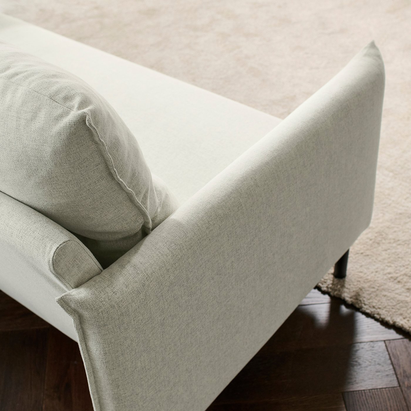Modern sofa with high back, soft cushions. Light-colored fabric, sleek design, black legs. Comfortable and elegant.