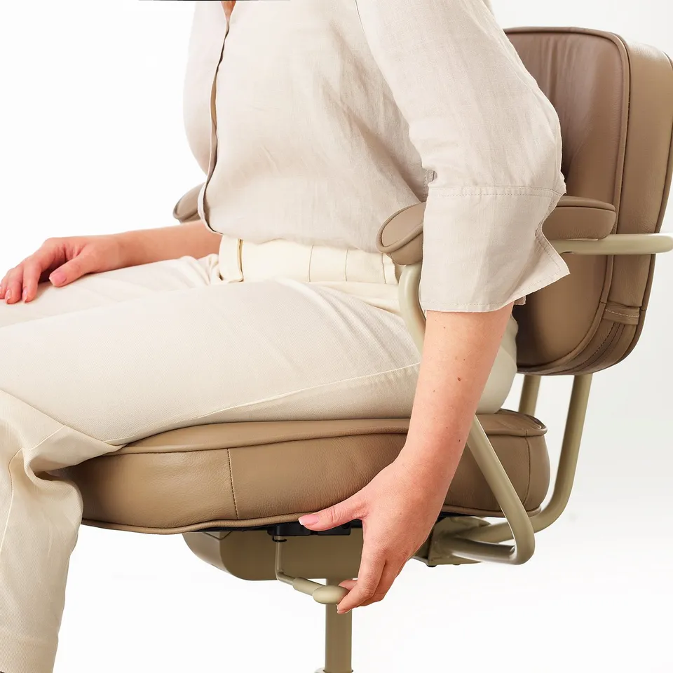 Person adjusting office chairs footrest, demonstrating its ergonomic function for comfort and support.