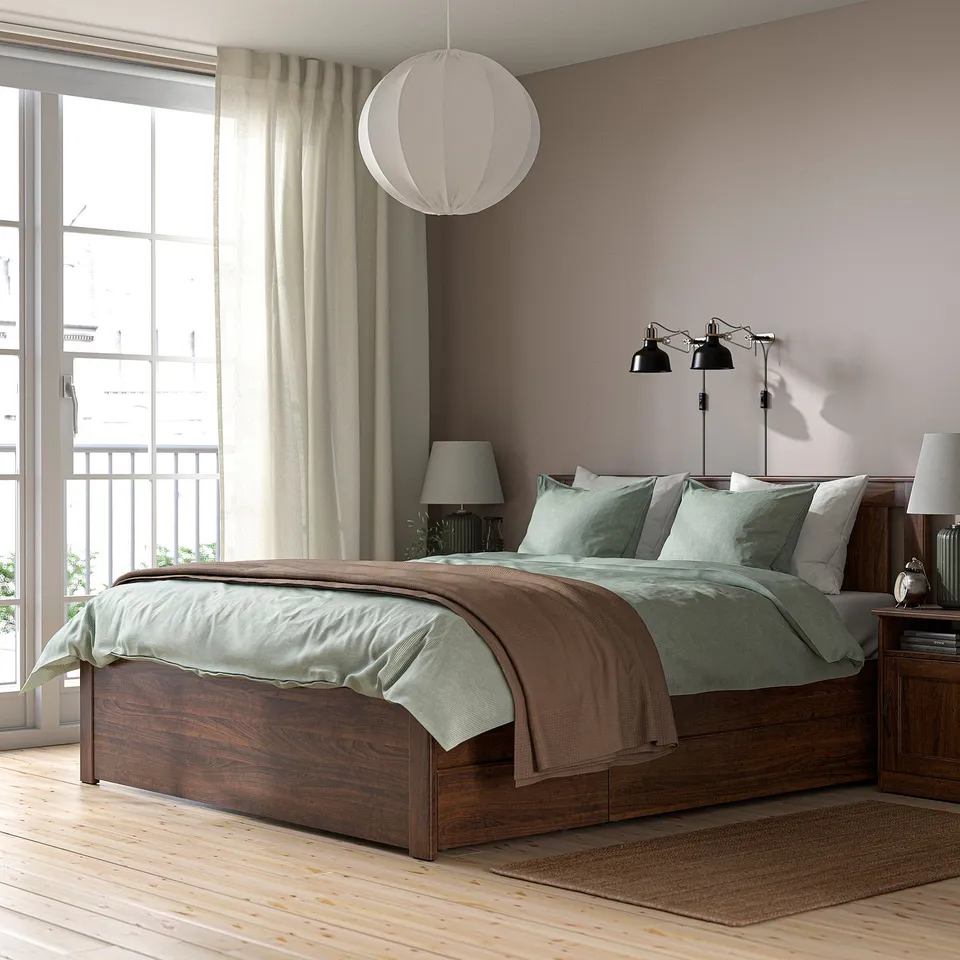 Brown SONGESAND bed frame with green bedding and high legs.