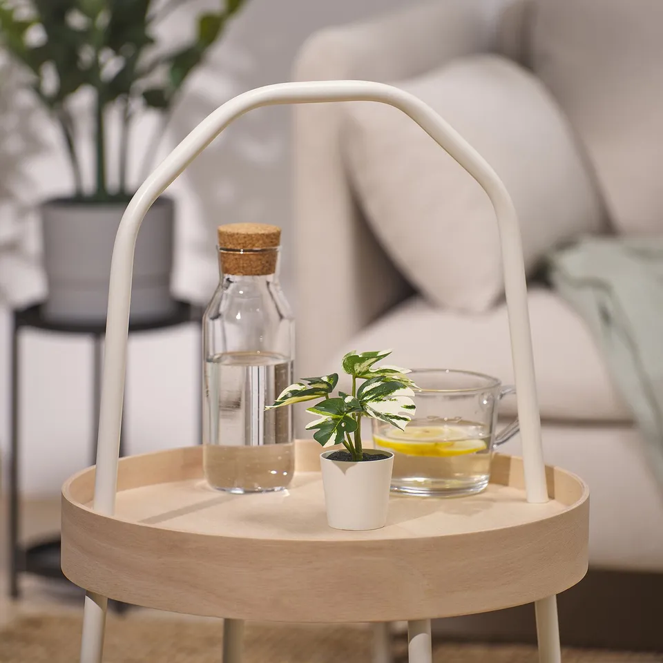 Minimalist modern tray with handle holds jar, small plant, cup. Trays round, light wood, metal legs.