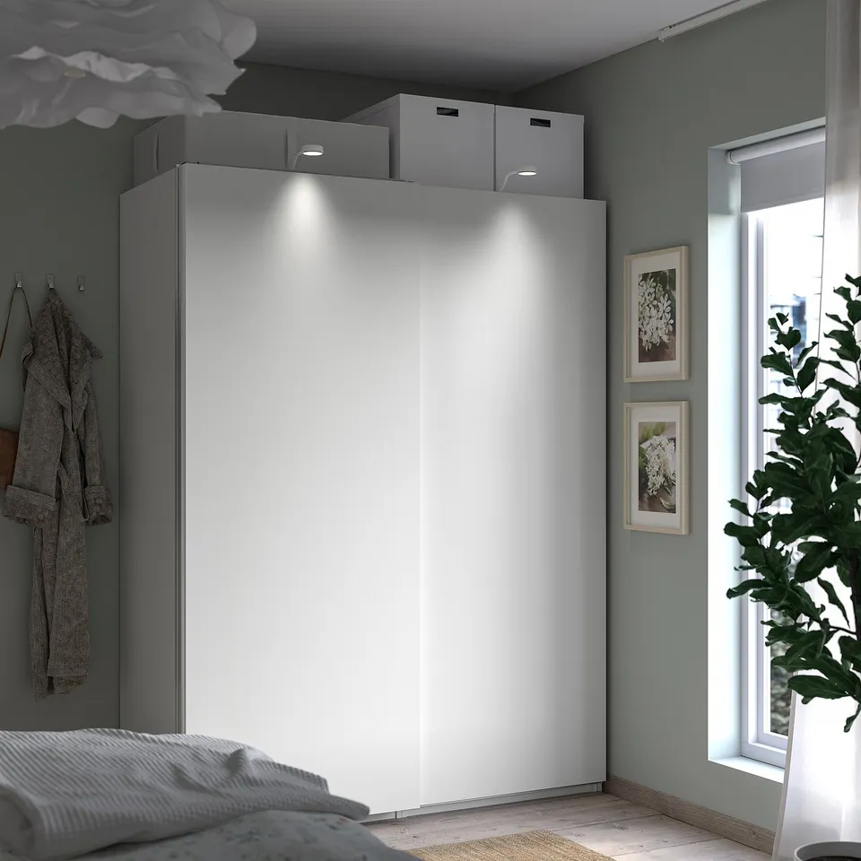Modern bedroom featuring PAX wardrobe in white with integrated lighting and sliding doors.