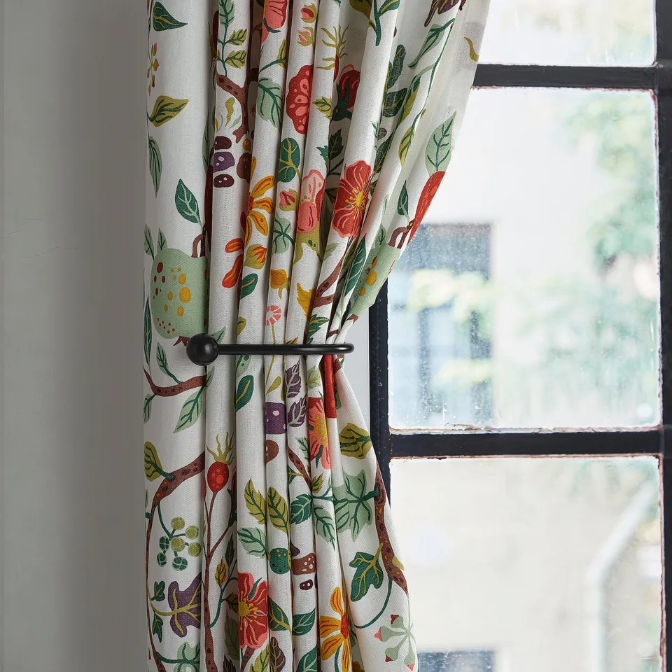 RÖRNICKA curtain tie-backs in black metal hold back floral-patterned curtains. Small, elegant, holds curtains near large window.