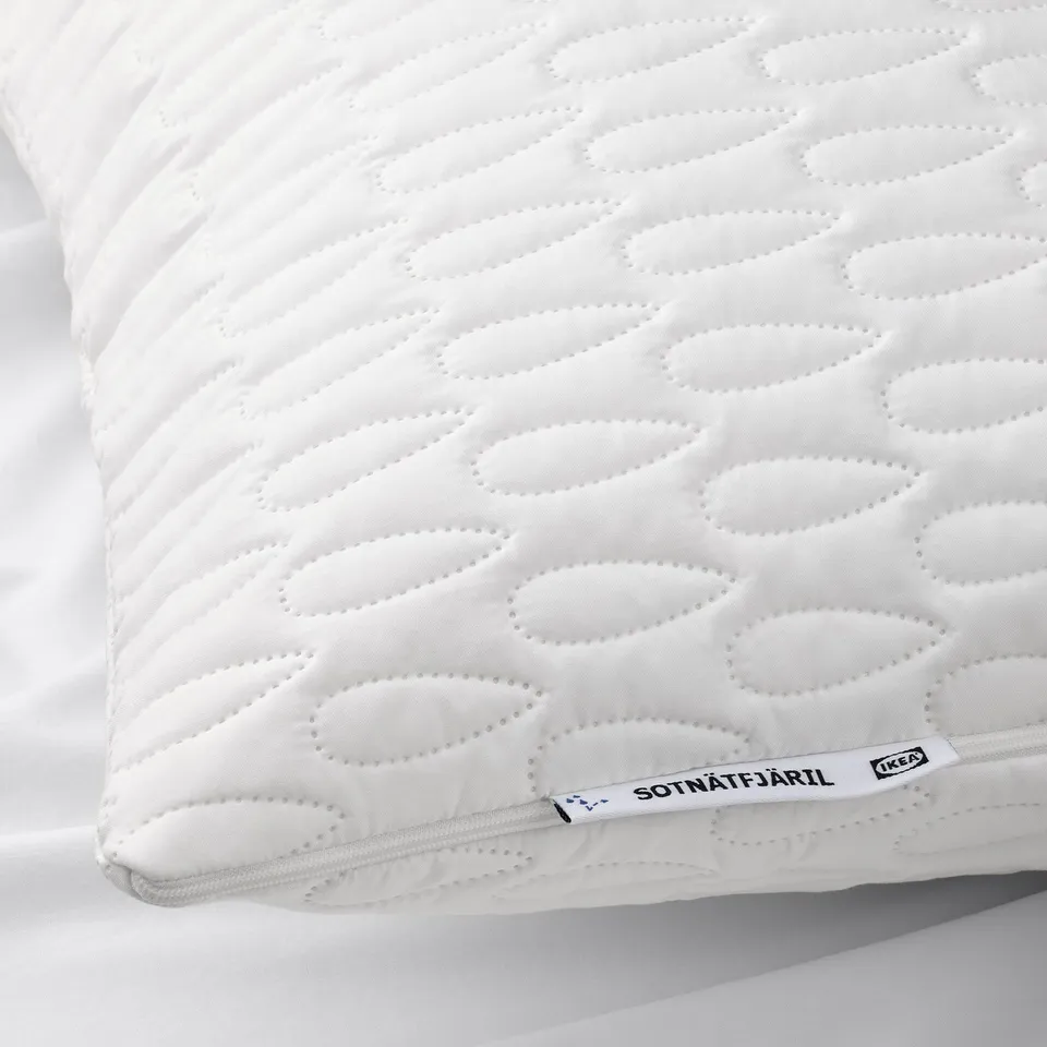 Close-up of a white pillow protector with a quilted pattern, showing the pillows zip and SOTNÄTFJÄRIL label from IKEA.
