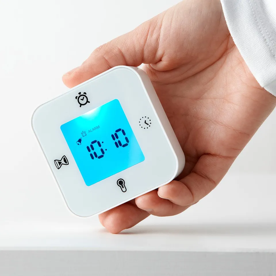 Hand holding a KLOCKIS multifunction digital clock displaying time 10:10.