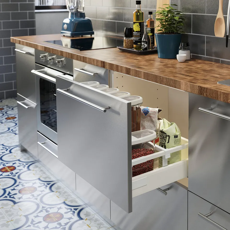 Modern kitchen with stainless steel oven and drawer open showing organised food storage containers on a wooden countertop.