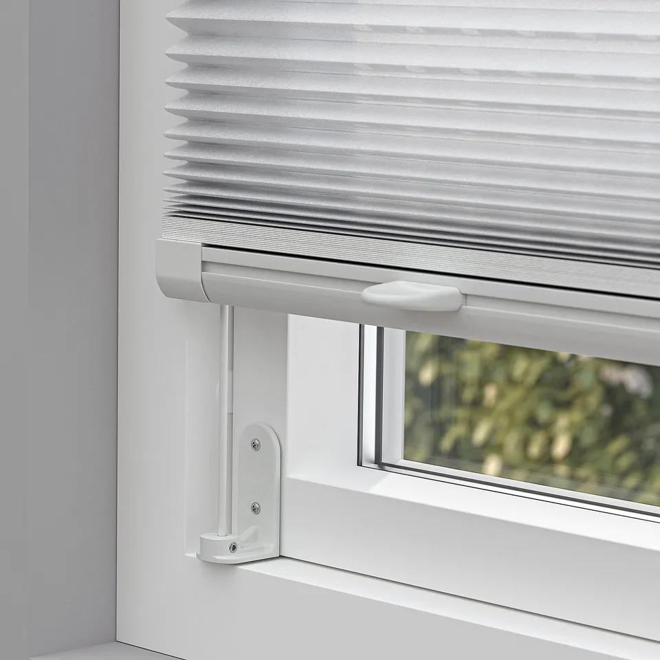 Close-up of cordless pleated blind, mounted on window with adhesive brackets, controlling light and privacy.