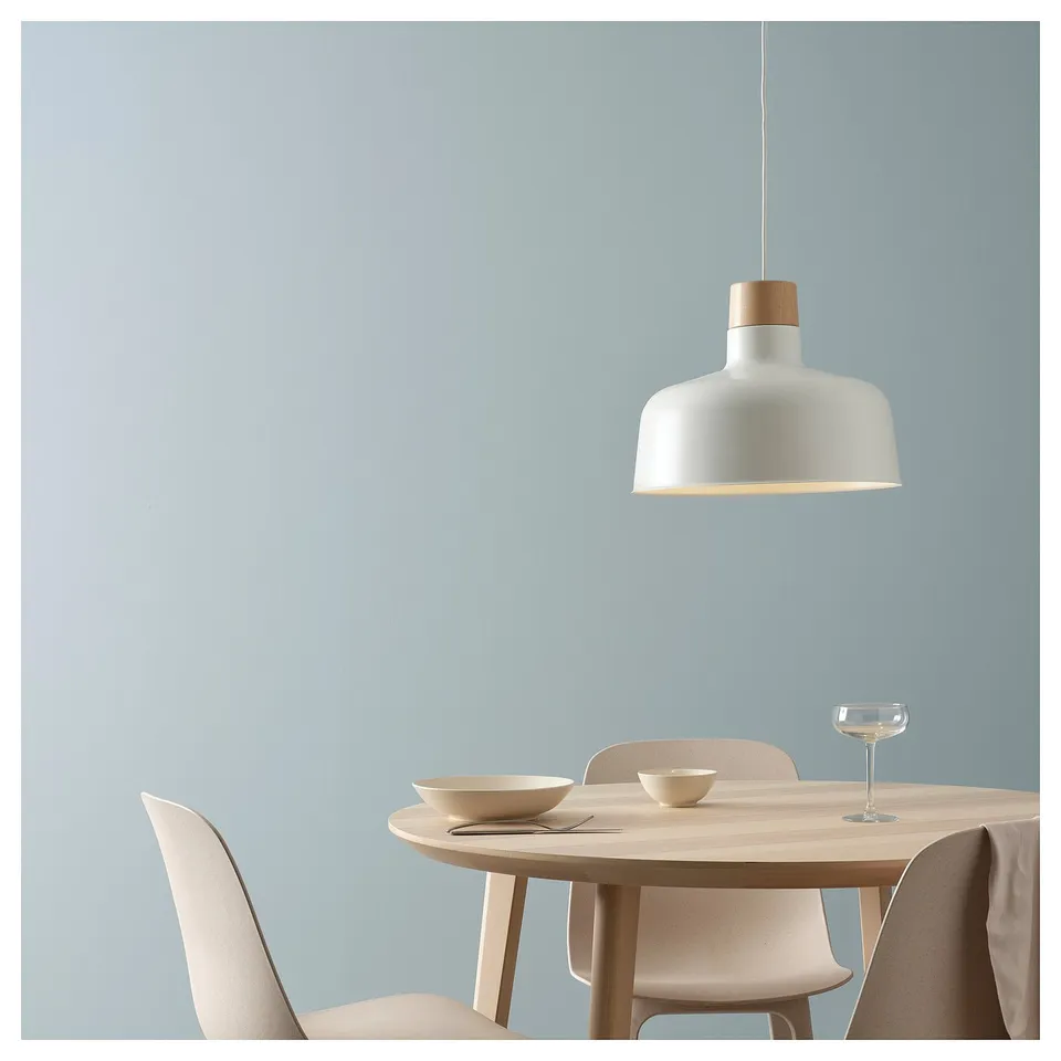 Modern dining room with blue walls, BUNKEFLO pendant lamp over wooden table with beige chairs.