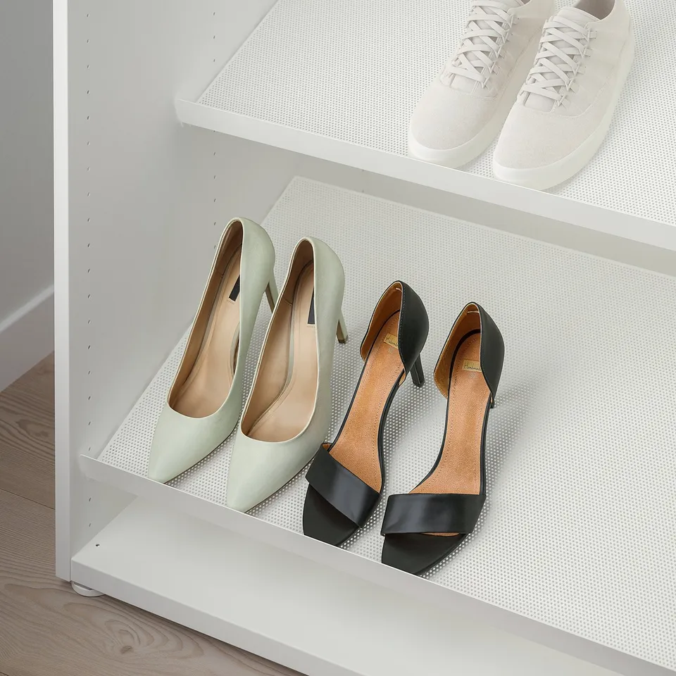 White shelves with two pairs of high heels, one green and one black, for organised storage.