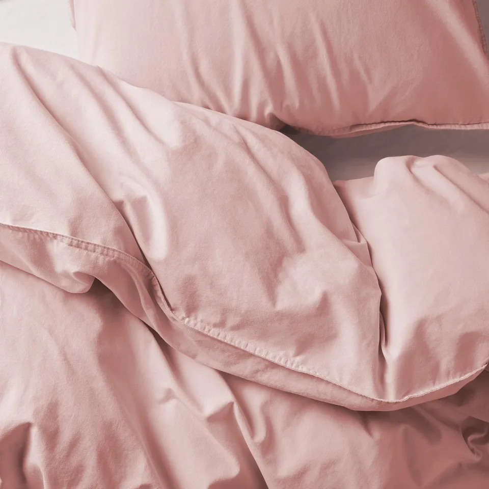 Neatly arranged pink bed sheets with duvet, smooth & inviting.