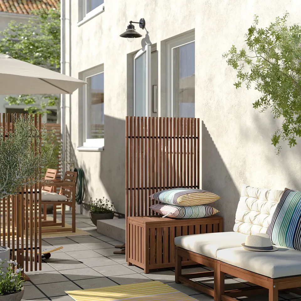 Outdoor patio with NÄMMARÖ wood furniture: lounge chair, privacy screen, and cushions, all in natural brown.