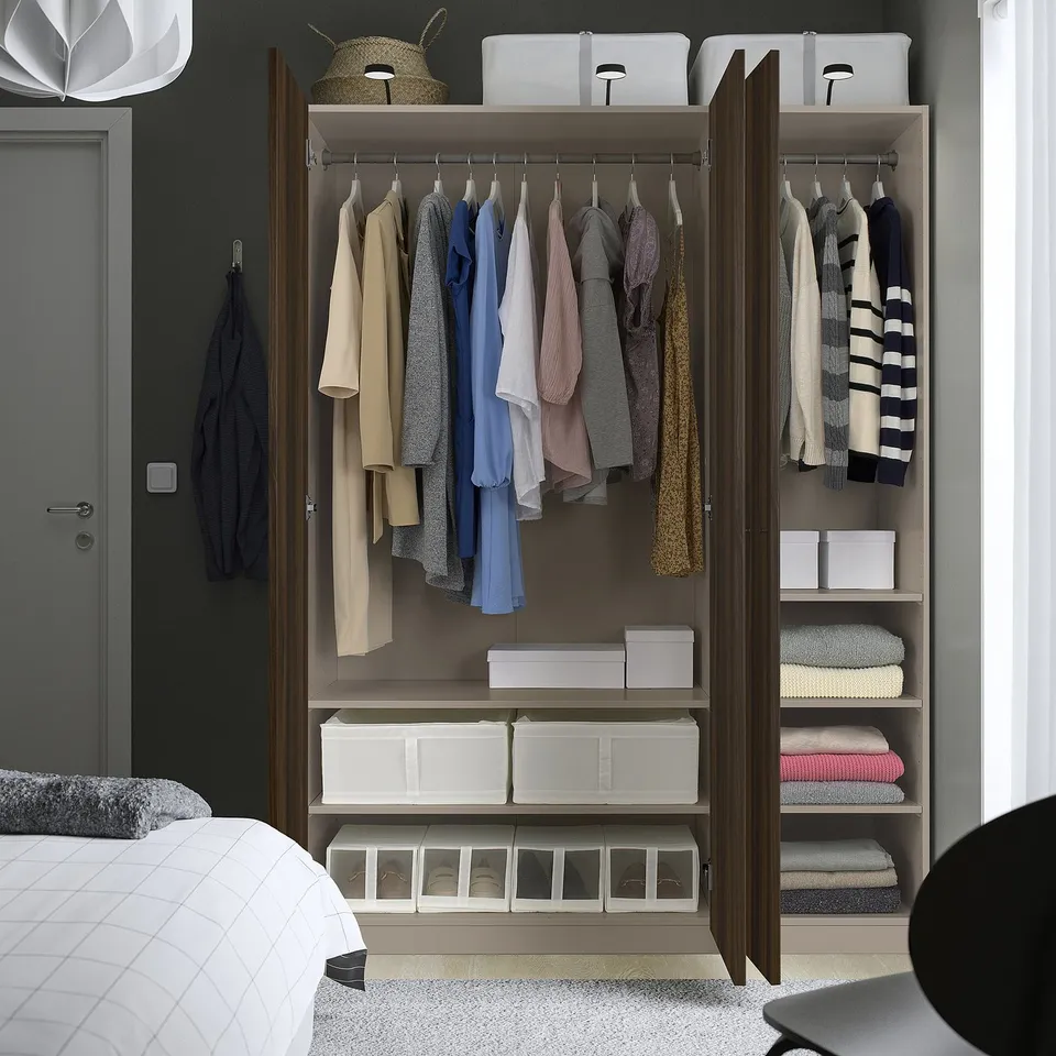 Bedroom closet with organised clothes and storage boxes. Clothes hang on rods, boxes on shelves, and a basket on top.