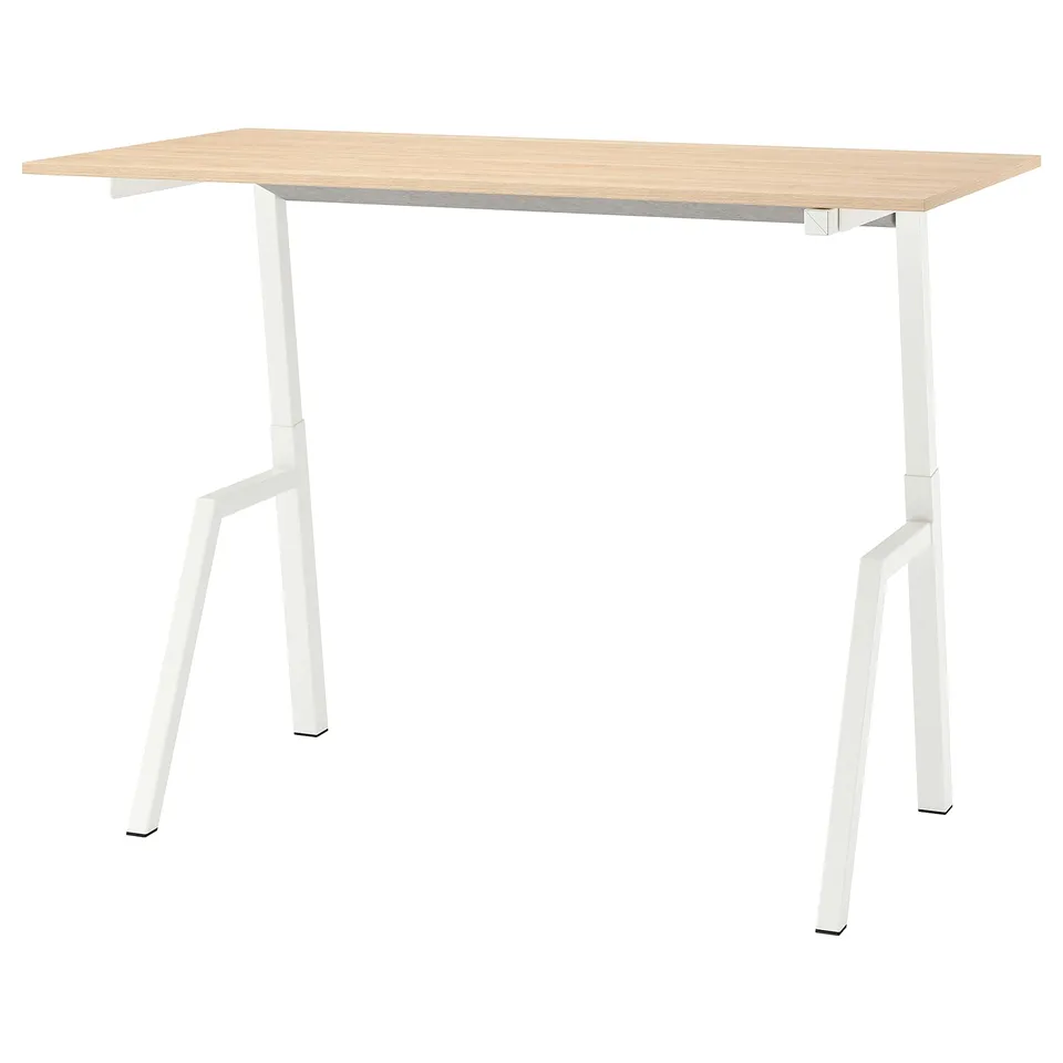 A trottén sit-stand desk in light oak colour with white legs. The desk a rectangular tabletop and adjustable metal legs for height variation.