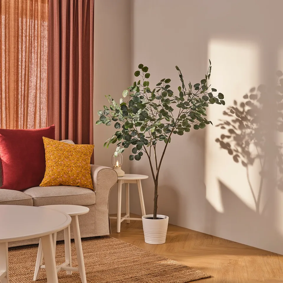 Living room with red curtains, beige sofa, and plant.