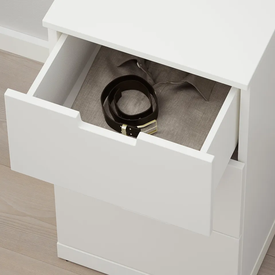 Open white NORDLI drawer with belt inside, showing storage and safety catch.