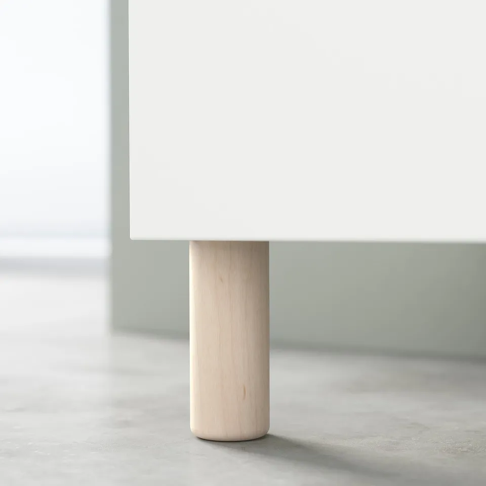 A single MEJARP leg, light wood colour, made of solid birch, supporting a white furniture piece.