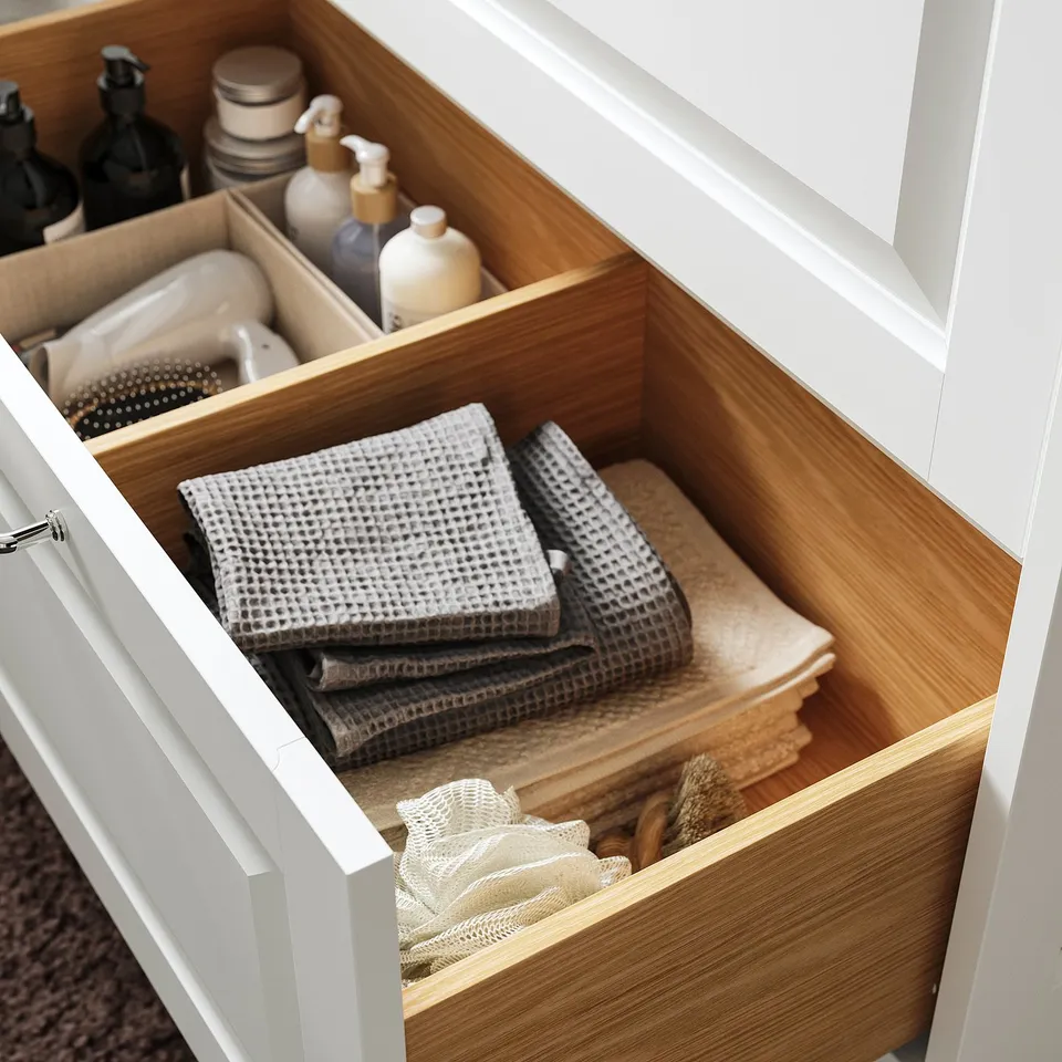 Organised bathroom drawer: folded towels, bottles, and toiletries.
