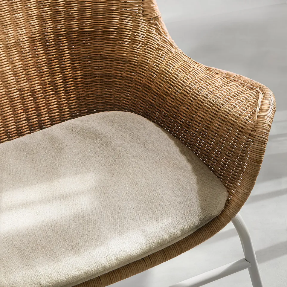 Close-up of woven wicker chair with beige cushioned seat, showcasing quality craftsmanship.