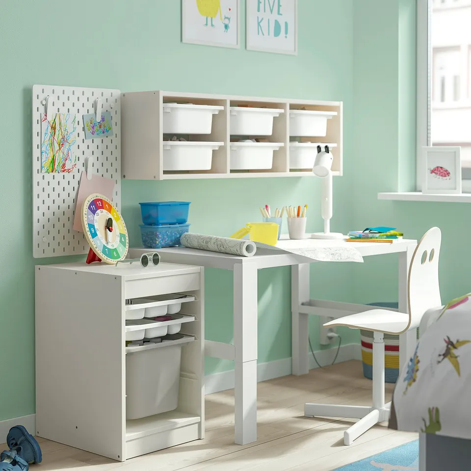 Childs study area with white TROFAST storage, pegboard, and desk. Bright, organised space with colourful supplies.