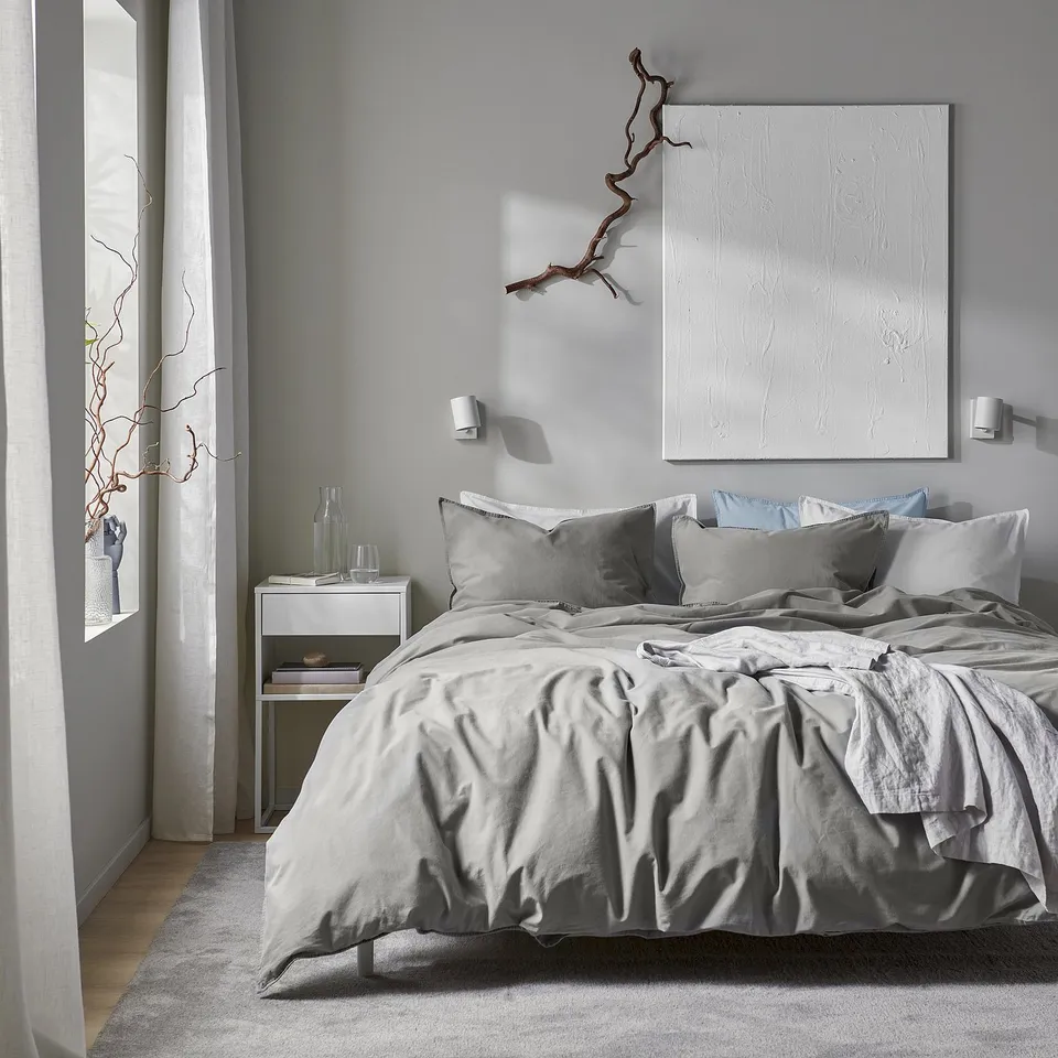 Bedroom with large bed in grey duvet, abstract painting above, spacious feel.