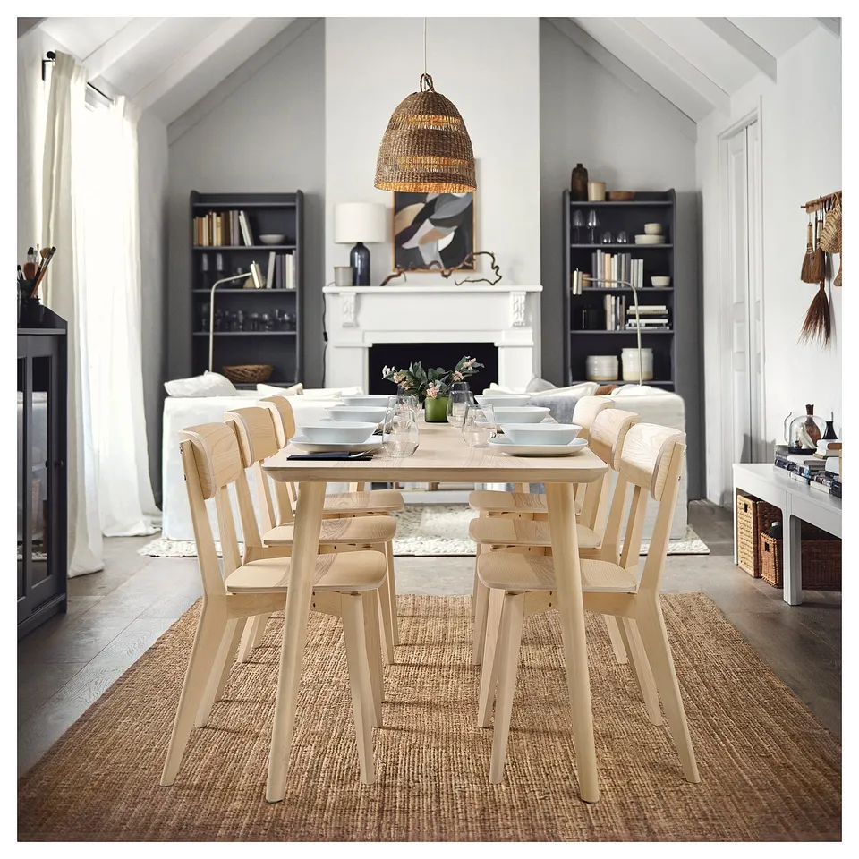 Modern dining room with wooden table, fireplace, & bookshelves. TORARED lamp hanging, emitting warm light.