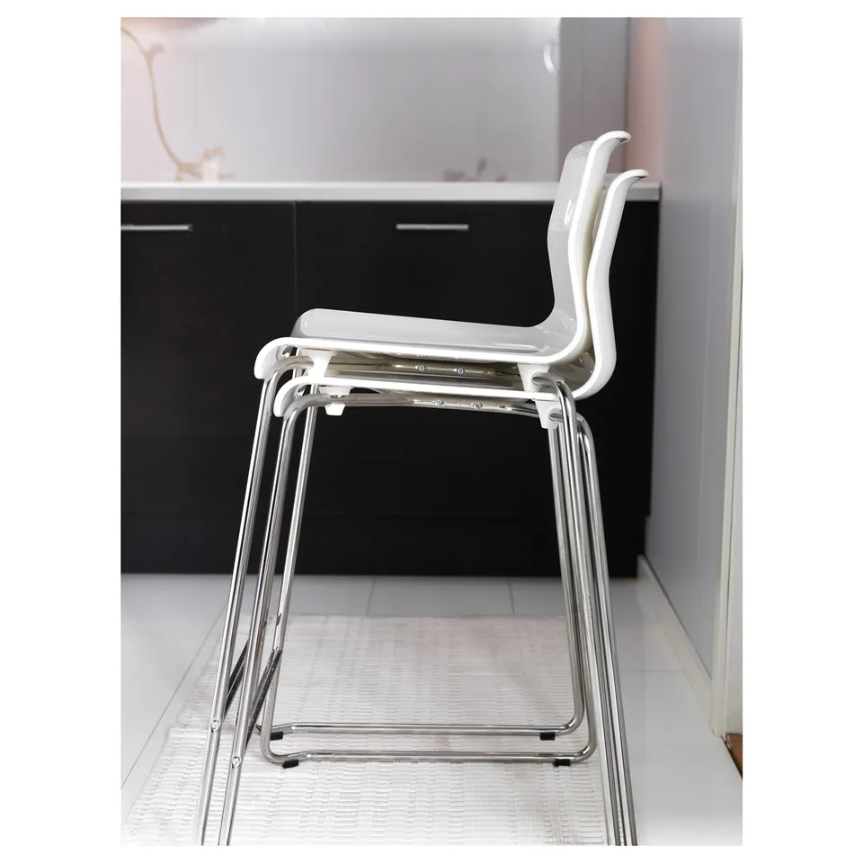 Stacked white plastic stools with chrome legs in modern room.